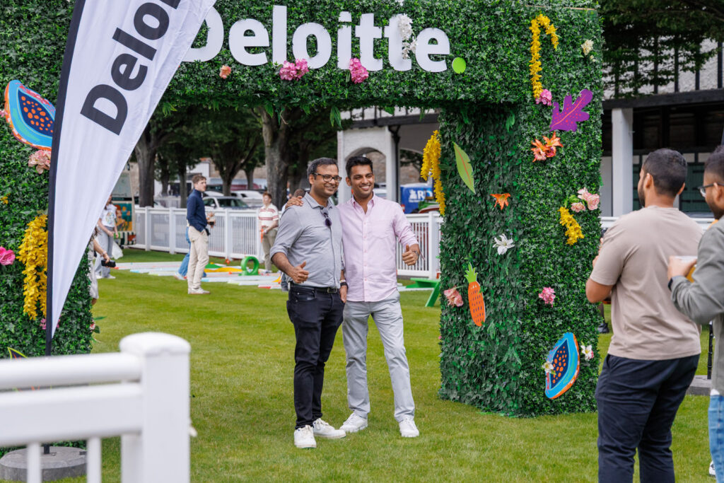 Two men smiling at a Deloitte outdoor event.