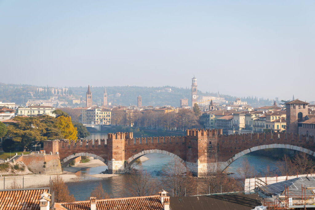 Verona's Castelvecchio Bridge and city skyline over Adige River.