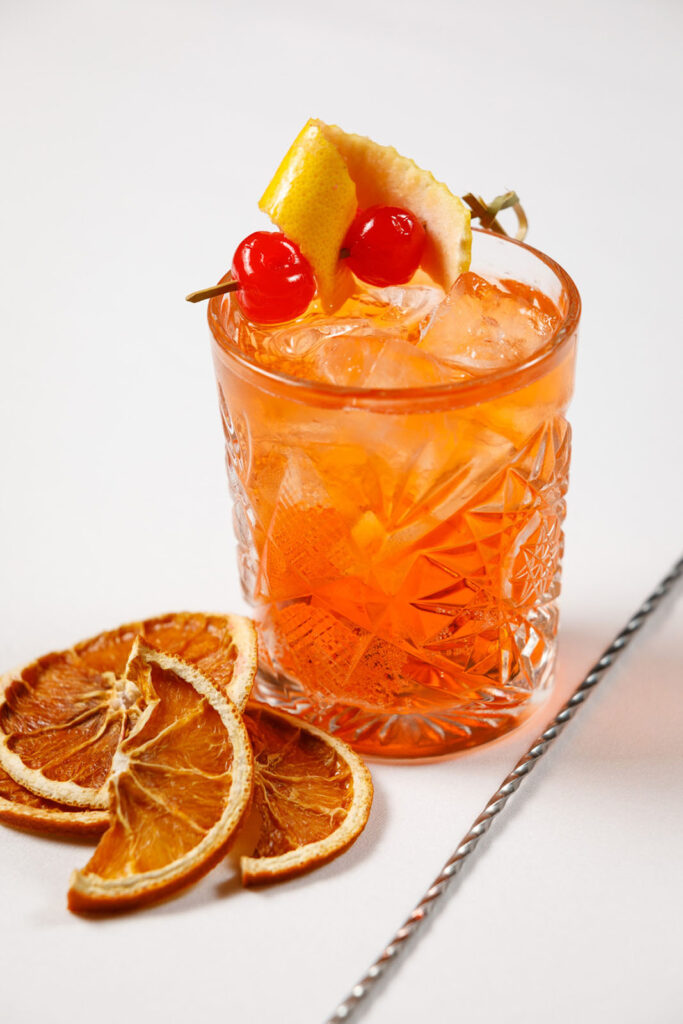 Vibrant orange cocktail with fruit garnish and dried oranges.