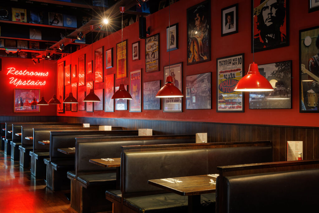 Vibrant red-walled diner with booths, music posters, and neon sign.