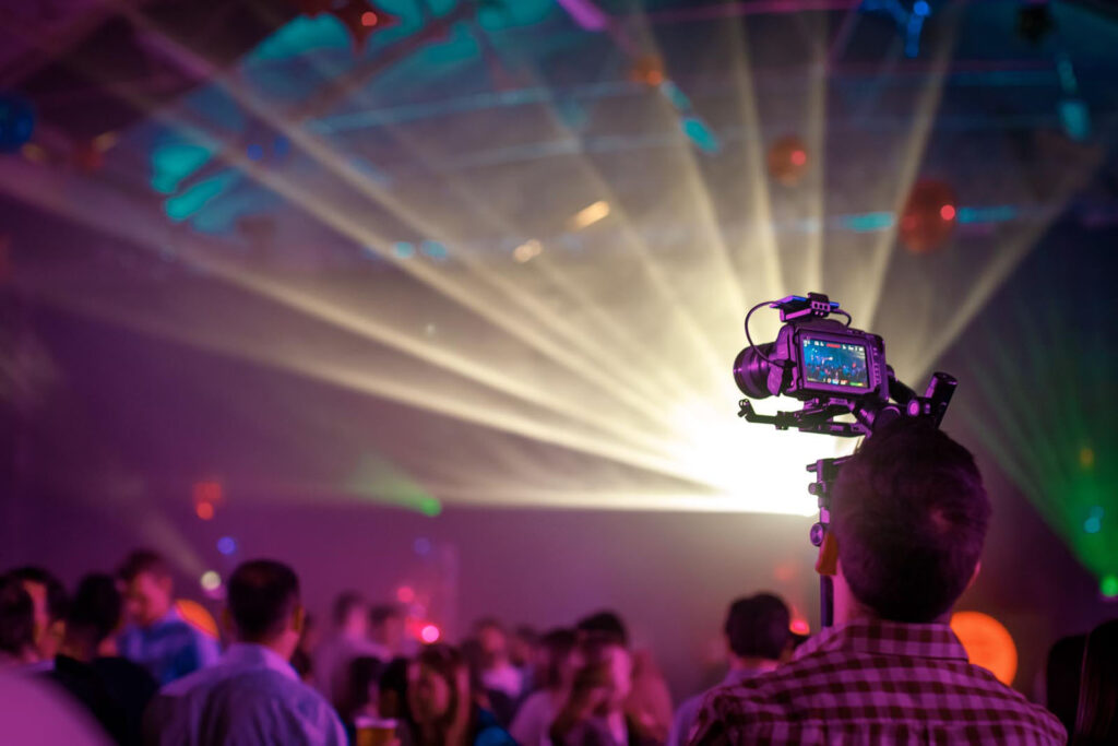 Videographer captures vibrant party scene with bright lights.