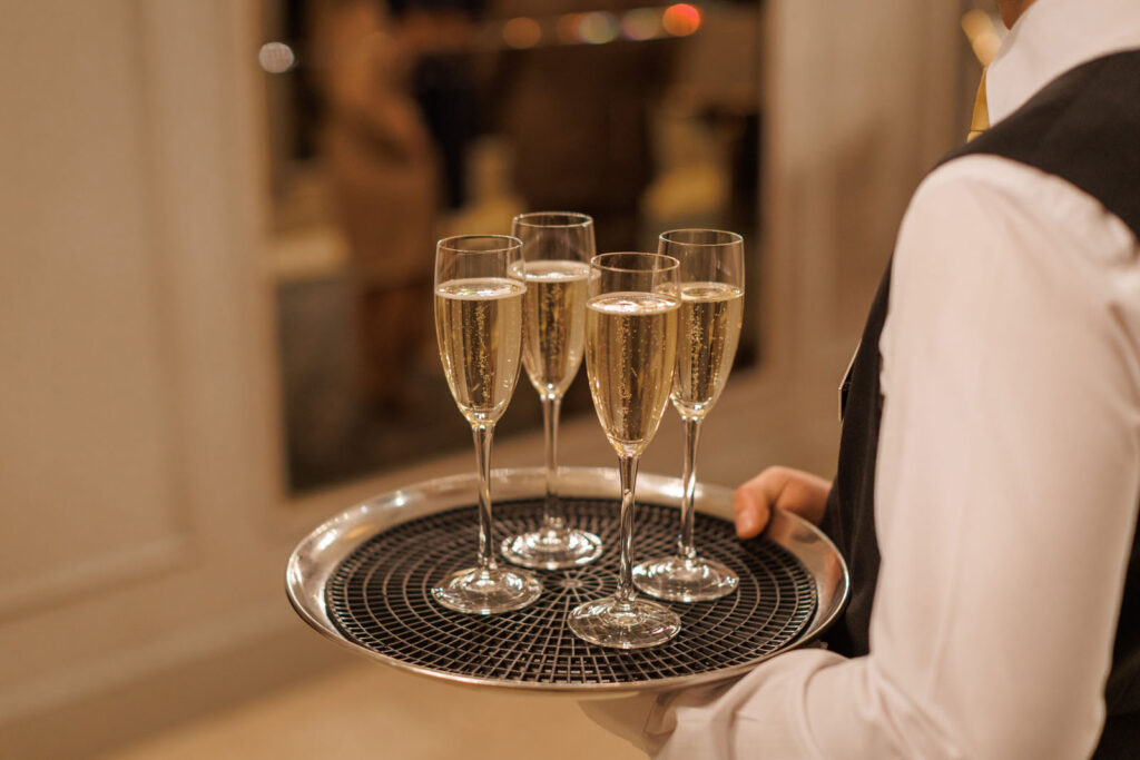 Waiter serving champagne glasses on a tray.