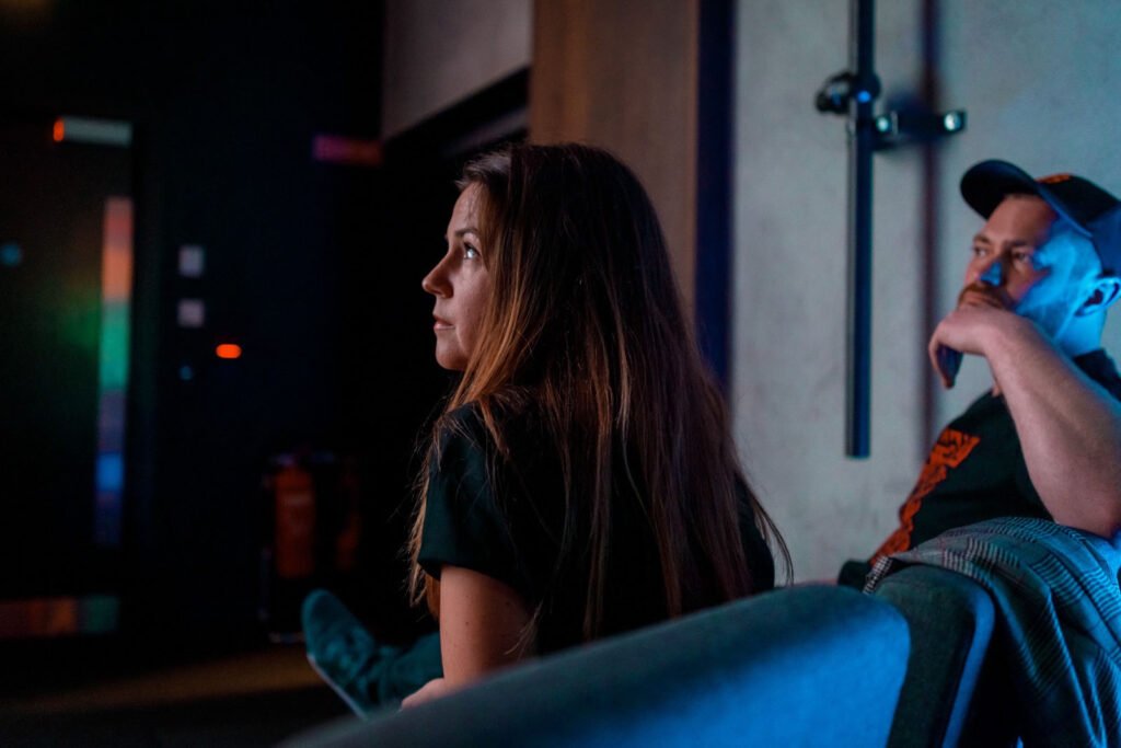 Woman and man watching intently in a dimly lit room.