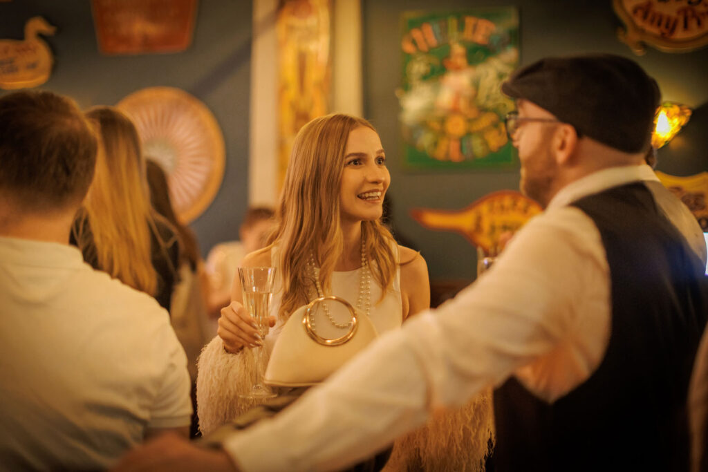 Woman smiling, holding drink, talking to man.