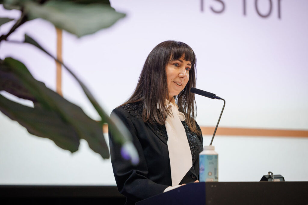 Woman speaking at a podium with a microphone.