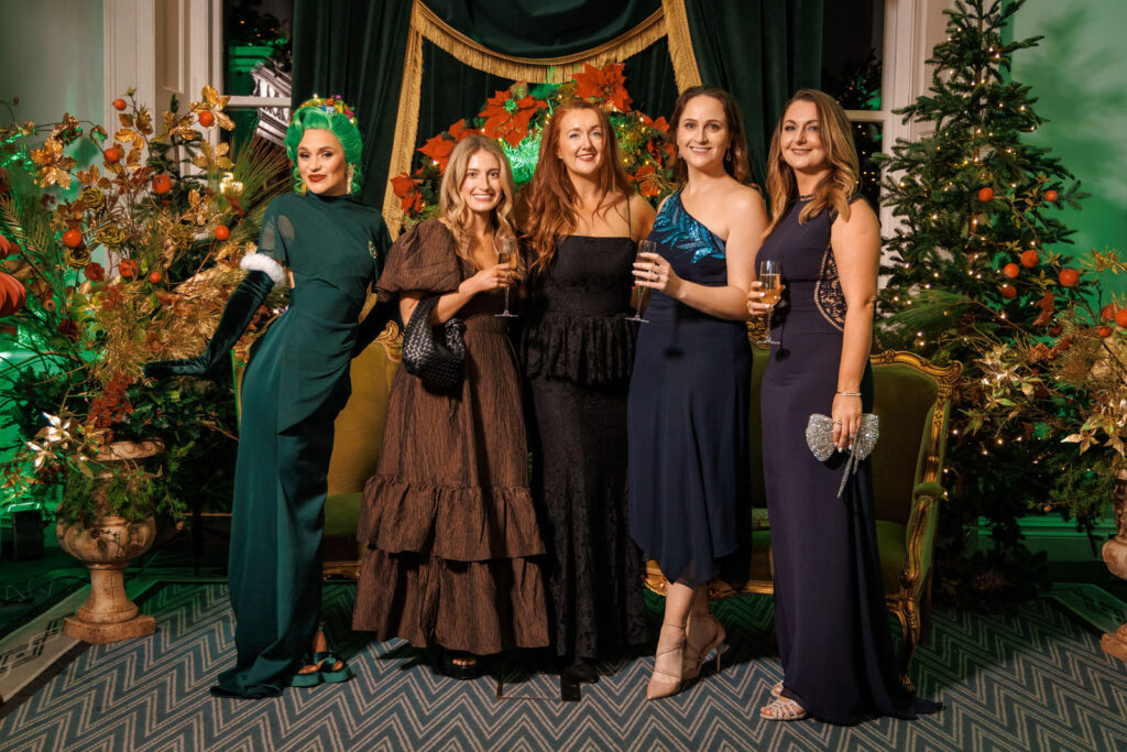 Women in formal wear celebrating amidst festive decorations.